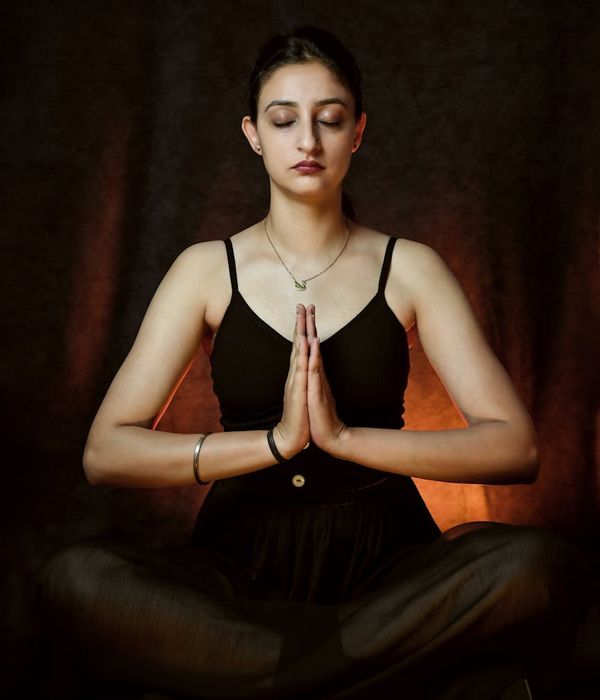 Woman in a calm, focused yoga pose against a dark background.