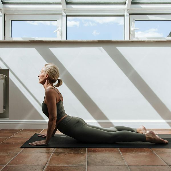 Woman stretching gracefully in a bright, sunlit room.